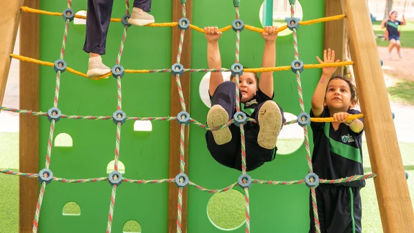 Students climbing on rope ladder at wellspring private school early childhood playground