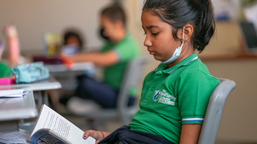 Student seated at desk reading a book for WellSpring Private School admissions