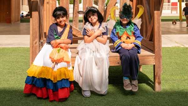 three elementary WellSpring Private School admissions students dressed in costume sitting on a bench