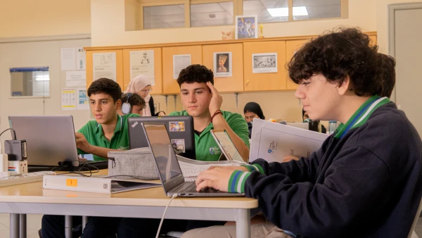 three male students at WellSpring Private School learning together on their computers