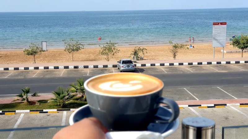 A cup of coffee overlooking a calm beach
